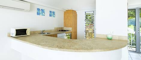 Una cocina moderna con una isla curva, electrodomésticos integrados y vistas a zonas verdes.