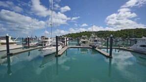 Un port esportiu amb diverses embarcacions amarrades, aigua tranquil·la i cel serè.