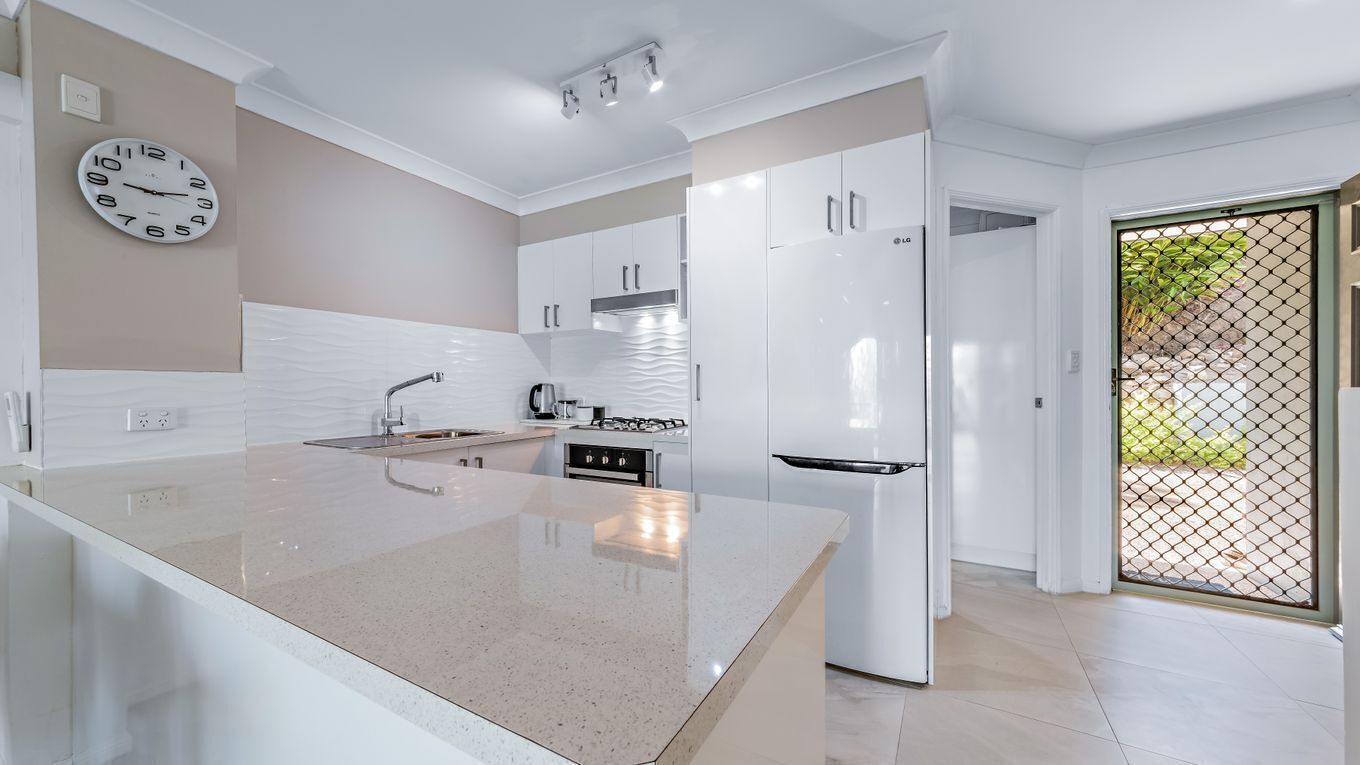 Una cocina moderna con armarios blancos, una isla central y un horno empotrado.