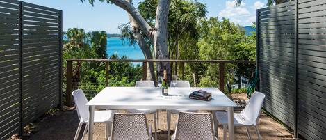 A patio with a table and chairs, a book, and a bottle of champagne.