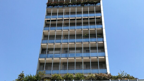 Um edifício moderno alto com uma grade de janelas e varandas.