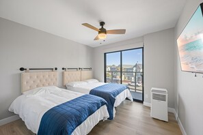 A bedroom with two beds, a ceiling fan, a large window with a view of buildings, and a wall-mounted air conditioner. - Newly remodeled- Panoramic Views- Last Minute Discount (San Diego)