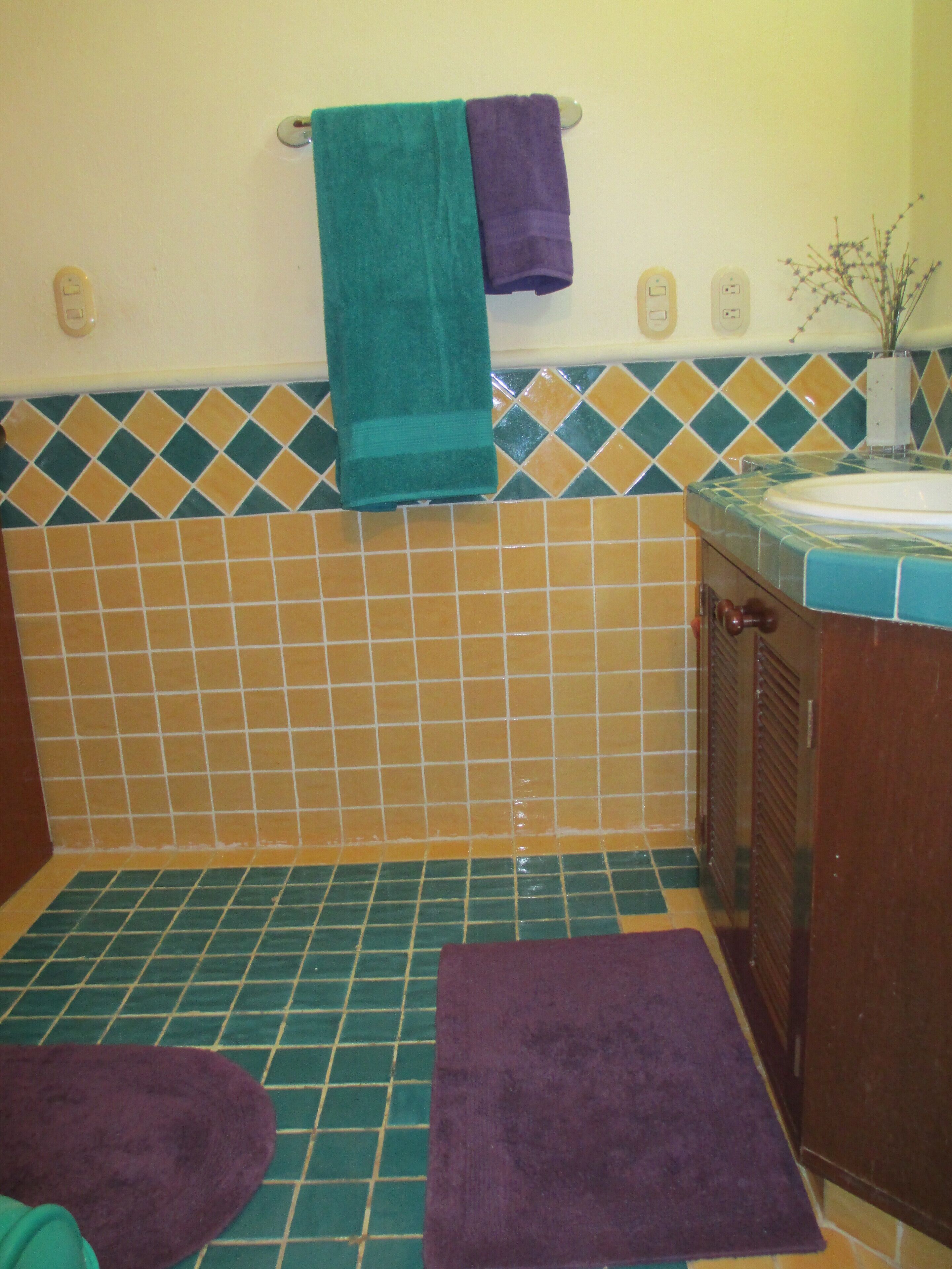 Ein Badezimmer mit gefliestem Boden, einem Waschbecken und zwei Handtüchern an einem Haken.