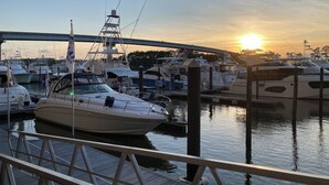 Una marina con barche ormeggiate, un ponte sullo sfondo e un tramonto.