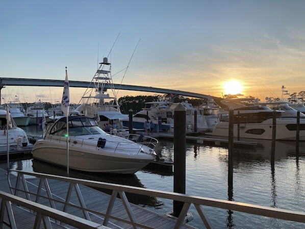 Un port de plaisance avec des bateaux amarrés, un pont en arrière-plan et un coucher de soleil.