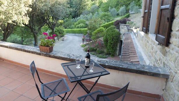 Eine Terrasse mit Tisch und Stühlen, einer Weinflasche und Blick auf einen Garten mit einem Weg.
