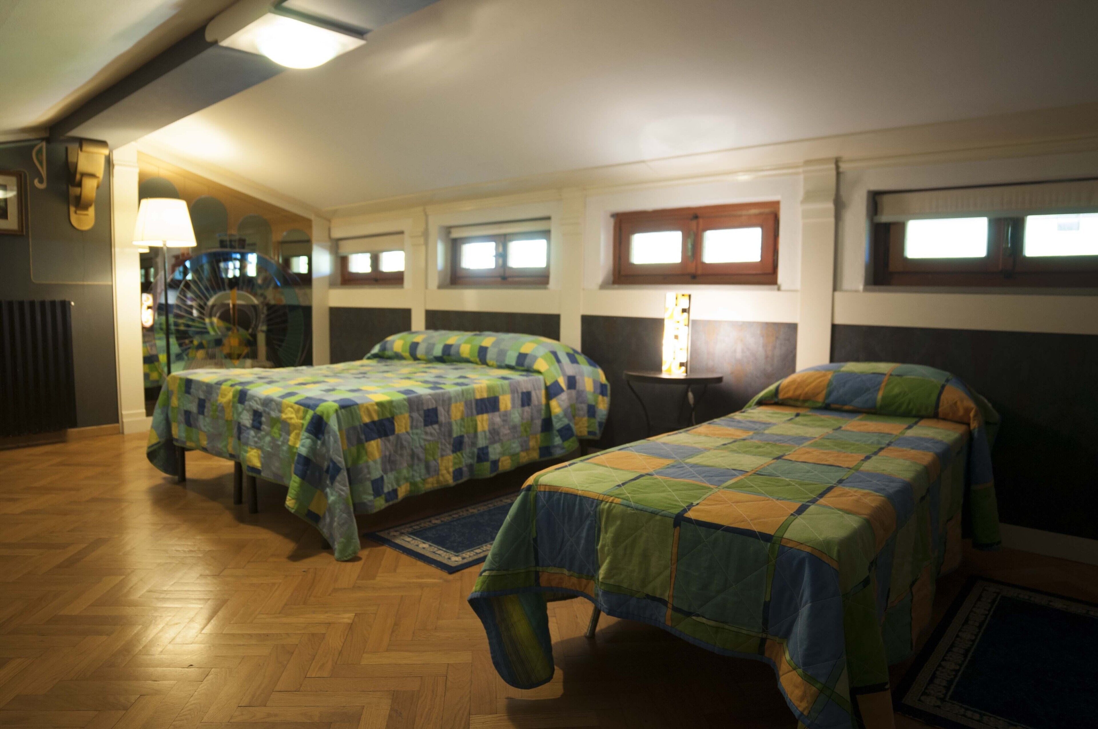 Une chambre avec deux lits, un plancher en bois et une petite table.