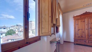 Ein Zimmer mit großem Fenster, Holzkasten und kleinem Tisch.