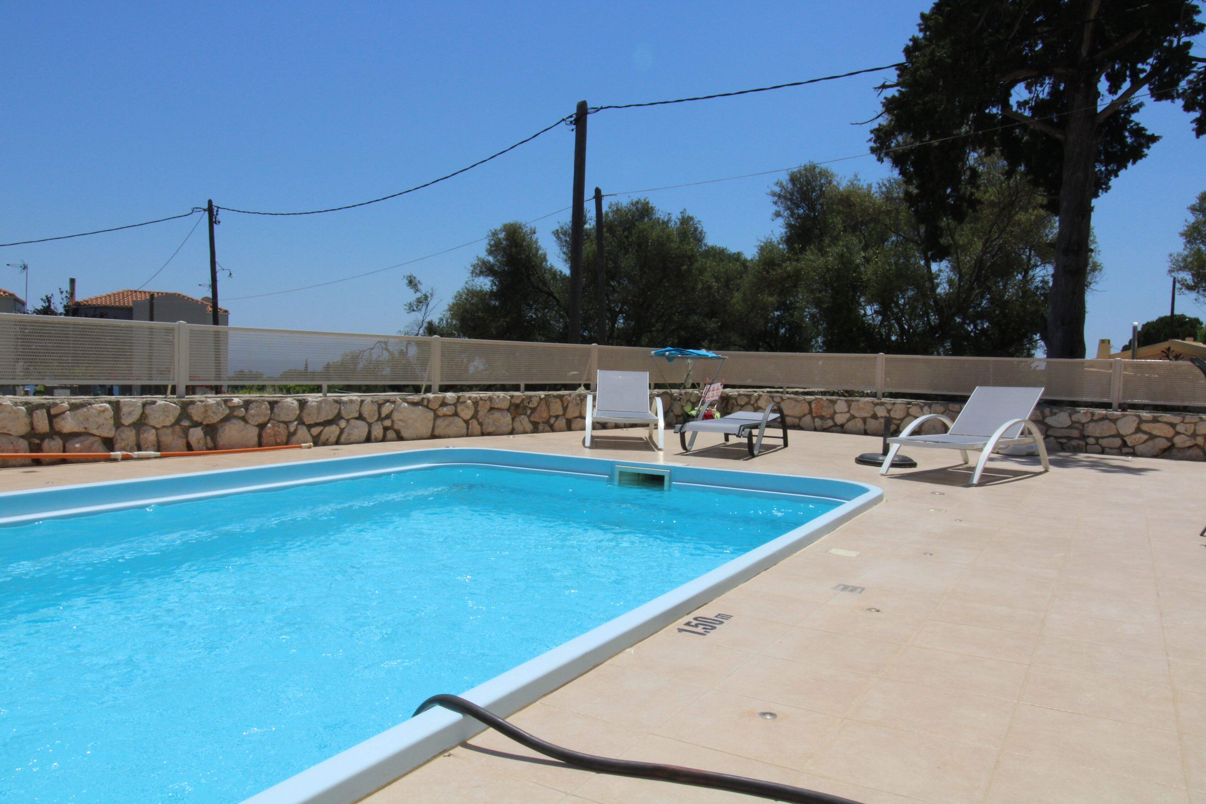 Une piscine avec des chaises longues et un mur en pierre.