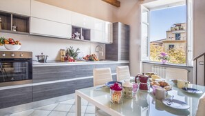 A modern kitchen with a dining area, featuring a large window, built-in cabinets, and a variety of kitchen appliances.