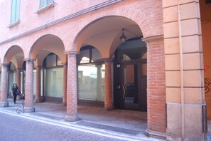 A building with a brick facade, arched doorways, and a pedestrian walkway. - The Jasmine Terrace Retreat: elegant and quiet apartment in the city center (Bologna)