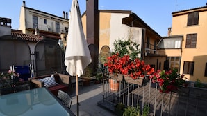 A courtyard with a glass table, outdoor seating, and red flowers.