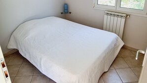 A bedroom with a bed, a radiator, a window, and a water dispenser.