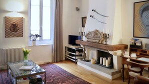 A cozy living room with a fireplace, a television, and a bookshelf.