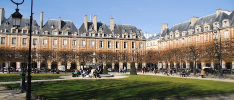A courtyard with a fountain, surrounded by historic buildings with multiple stories and large windows.