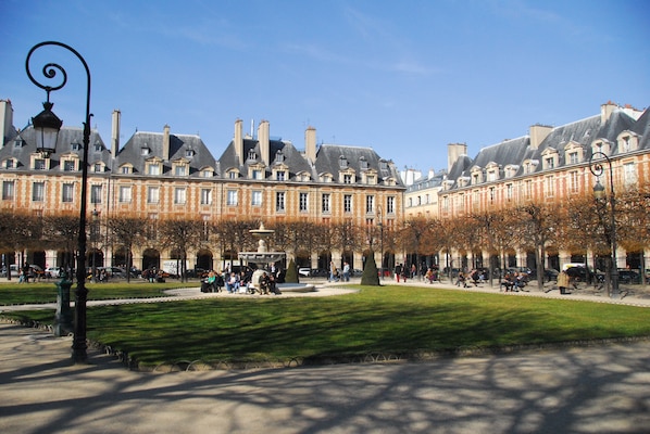 A courtyard with a fountain, surrounded by historic buildings with multiple stories and large windows.