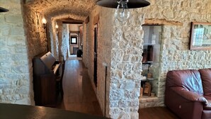 Ein rustikales Interieur mit Steinwänden, Holzdielen, einem Ledersofa und einem Klavier.
