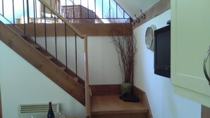 A staircase with wooden steps and a metal railing. There is a dining table with plates, a wine bottle, and cutlery. A potted plant is placed near the staircase. - Comfortable Barn, Ashdown Forest, Fantastic Local Pub, Excellent For Walkers (Danehill, Haywards Heath)