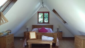 A bedroom with a sloped ceiling, a wooden bed, two nightstands, a window, and a wooden dresser. - Comfortable Barn, Ashdown Forest, Fantastic Local Pub, Excellent For Walkers (Danehill, Haywards Heath)