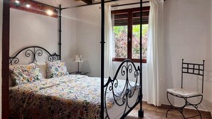 Une chambre à coucher avec un lit à baldaquin, une petite table et une fenêtre avec des rideaux.