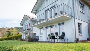 Een gebouw met twee verdiepingen, een balkon, terras en een verzorgd gazon.
