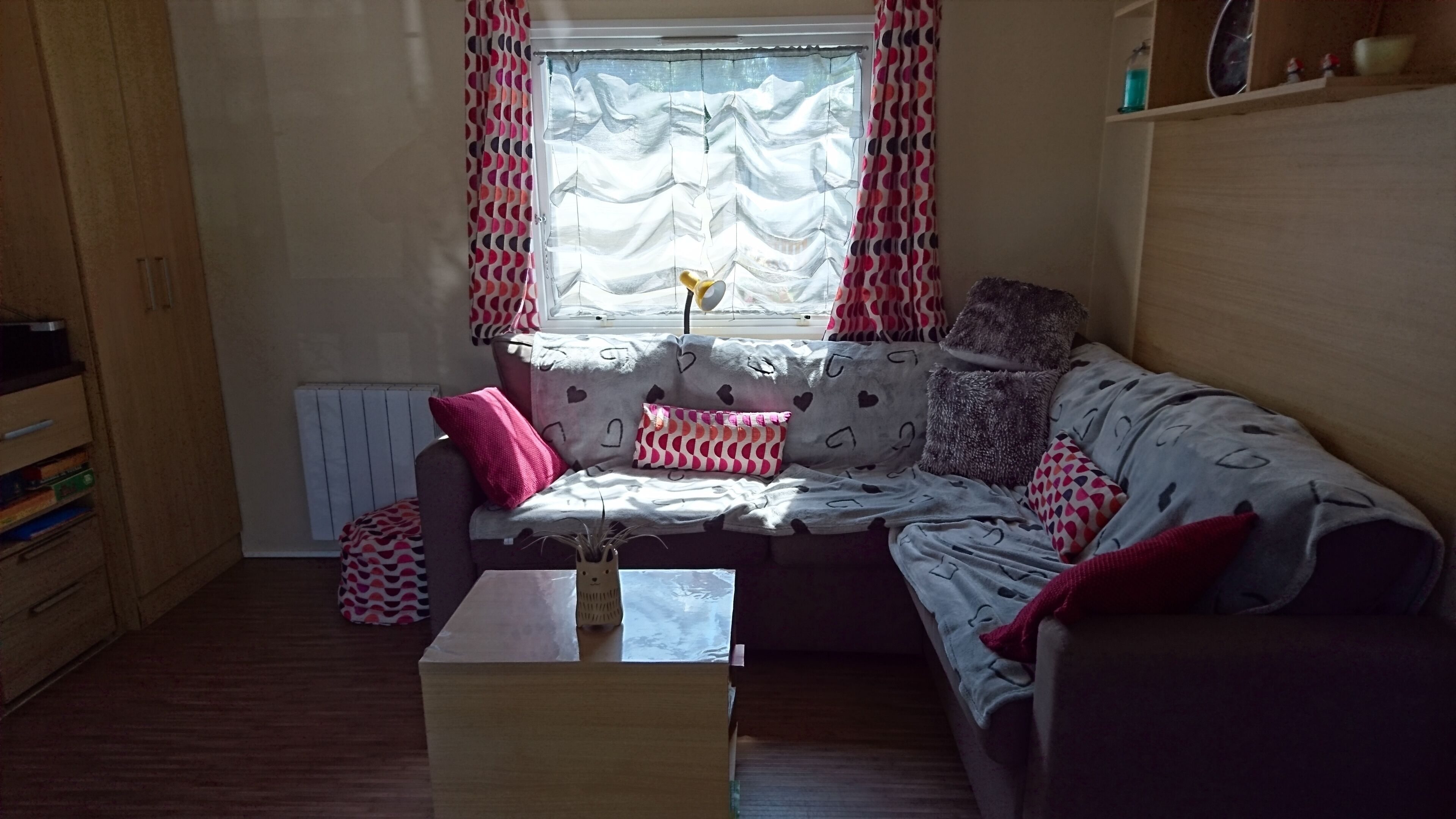 A cozy living room with a sofa, cushions, a small table, and a window with curtains.