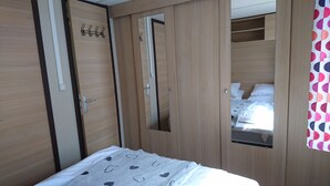Ein Schlafzimmer mit Bett, Holzschrank und Spiegel.
