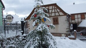 Een met sneeuw bedekte kerstboom voor een traditioneel vakwerkhuis.