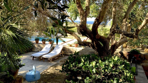 A poolside area with lounge chairs, a stone wall, and potted plants. - CALM - ZENITUDE - ONE OF THE MOST BEAUTIFUL HOUSES OF GOZO (GHARB)