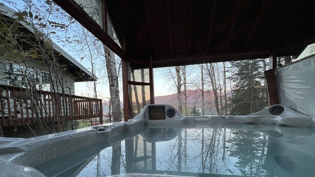 Un jacuzzi con cubierta de madera y vista a árboles y montañas.