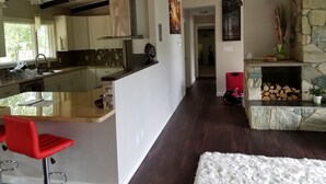 Una cocina moderna con una isla central, un comedor con sillas rojas y una chimenea de piedra.