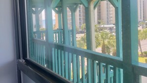 A view through a window with a green railing, overlooking a building with multiple floors and balconies. - Beautiful Condo Steps to the Gulf!  (Gulf Shores)