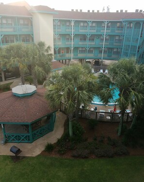 A multi-story building with balconies, a gazebo, and a fenced pool area. - Beautiful Condo Steps to the Gulf!  (Gulf Shores)