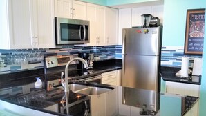 Una cocina moderna con electrodomésticos de acero inoxidable, encimera negra y armarios blancos.