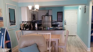 Una cocina moderna con una isla central, muebles blancos y electrodomésticos de acero inoxidable.