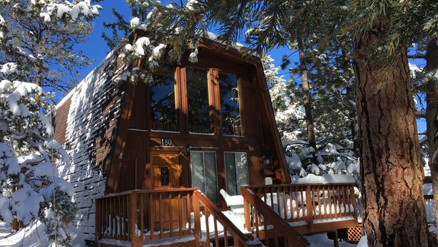 A wooden cabin with a number '180' on the door, surrounded by snow-covered trees. - Sugarloaf Cabin sweet cabin (Big Bear)