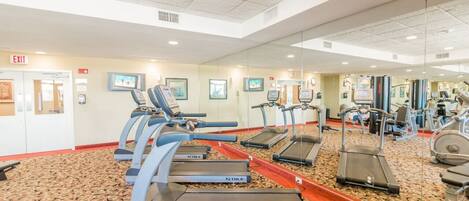 A gym with multiple treadmills, exercise bikes, and a mirrored wall.