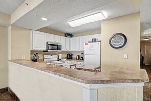 A compact kitchen with white cabinets, a microwave, a refrigerator, and a coffee maker.