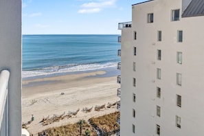 Ein Strandhotel mit mehreren Etagen, Balkonen und Blick auf das Meer.