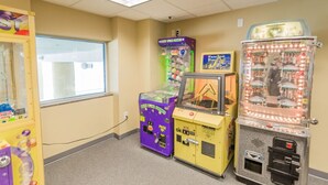A room with three arcade machines, a window, and a ceiling light. - 4BR/3BA, Sleeps 16, Large Oceanfront, Balcony (Myrtle Beach)