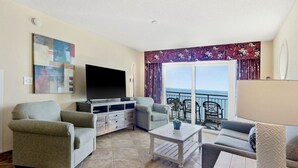 A living room with a flat-screen TV, two sofas, a coffee table, and a balcony with a view of the sea. - 4BR/3BA, Sleeps 16, Large Oceanfront, Balcony (Myrtle Beach)