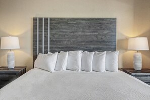 A bed with white bedding, a grey and white wall, and two bedside tables with lamps.