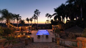 An outdoor swimming pool with a stone pathway leading to it, surrounded by palm trees and string lights. - Magical Beach House with Unforgettable Ocean Views (Todos Santos)