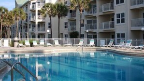 Un hotel de varios pisos con balcones, piscina y palmeras.