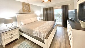 Un dormitorio con cama, mesita de noche, lámpara, ventilador de techo y televisor.