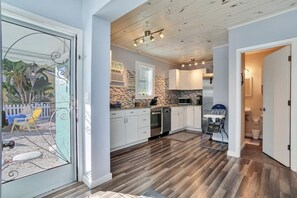 A modern kitchen with white cabinets, a stone backsplash, and a wooden ceiling. - 50 Steps to Beach Villa Hot Tub 1bd modern cottage (Bradenton Beach)