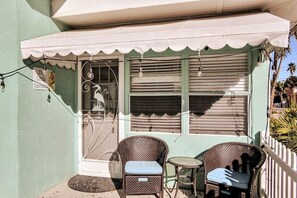 A small outdoor seating area with wicker chairs and a table, a white awning, and a sign reading "The Little Mermaid." - 50 Steps to Beach Villa Hot Tub 1bd modern cottage (Bradenton Beach)