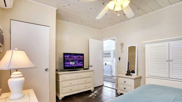 Une chambre à coucher avec un lit, une télévision, une commode et une lampe.