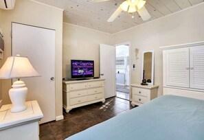 Ein Schlafzimmer mit Bett, Fernseher, Kommode und Lampe.