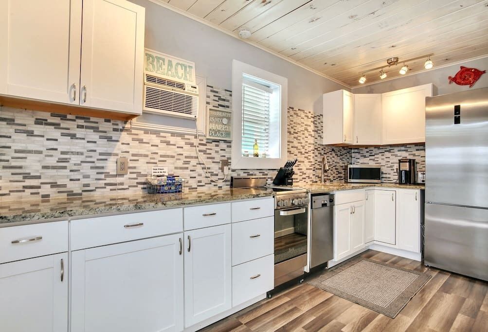 A modern kitchen with white cabinets, a stainless steel refrigerator, and a tiled backsplash.